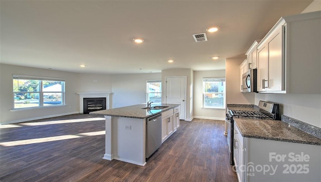 kitchen featuring appliances with stainless steel finishes, white cabinetry, sink, dark hardwood / wood-style flooring, and a kitchen island with sink