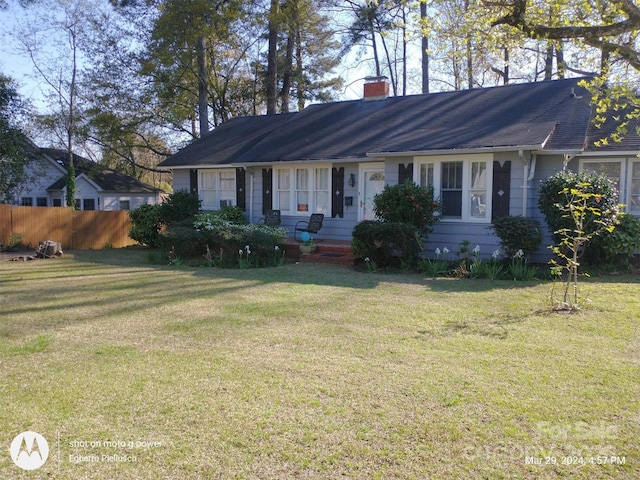 ranch-style house with a chimney, a front yard, and fence