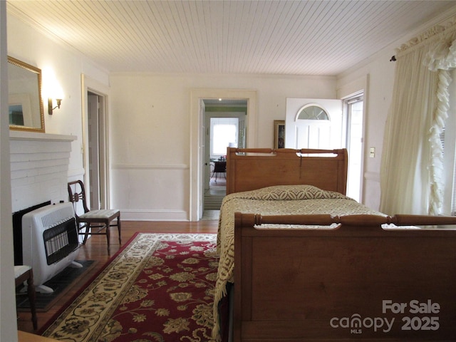 bedroom with heating unit, wood ceiling, ornamental molding, and wood finished floors
