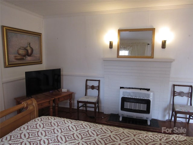 bedroom featuring heating unit, crown molding, a fireplace, and wood finished floors