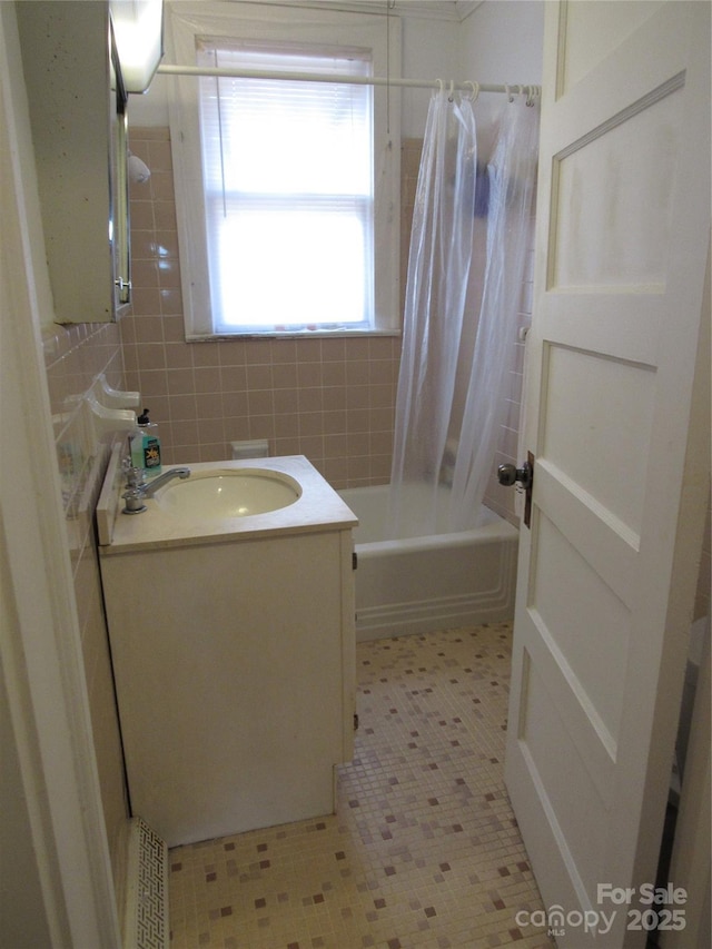 bathroom with tile walls, vanity, and shower / bath combo