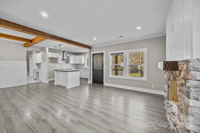 unfurnished living room with crown molding, hardwood / wood-style floors, and beam ceiling