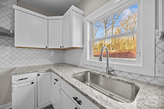 kitchen featuring white cabinetry, sink, and light stone countertops