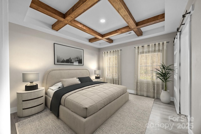 bedroom featuring beamed ceiling, a barn door, coffered ceiling, and light hardwood / wood-style floors