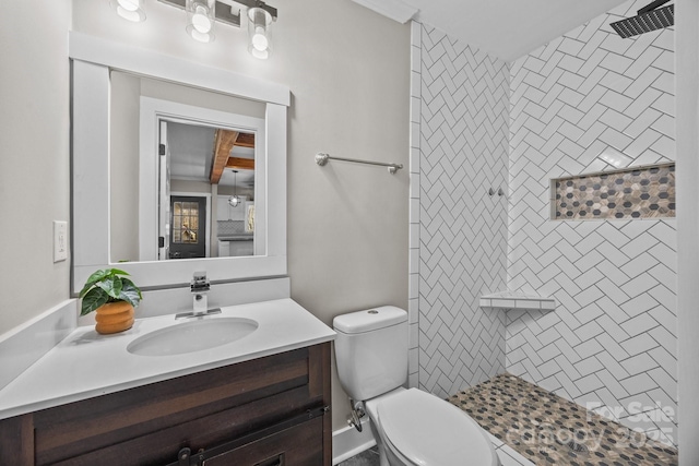 bathroom with tiled shower, vanity, and toilet