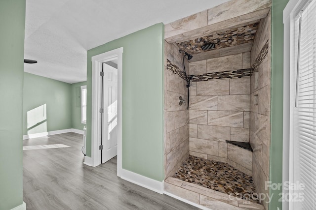 bathroom with a tile shower, hardwood / wood-style floors, and a textured ceiling