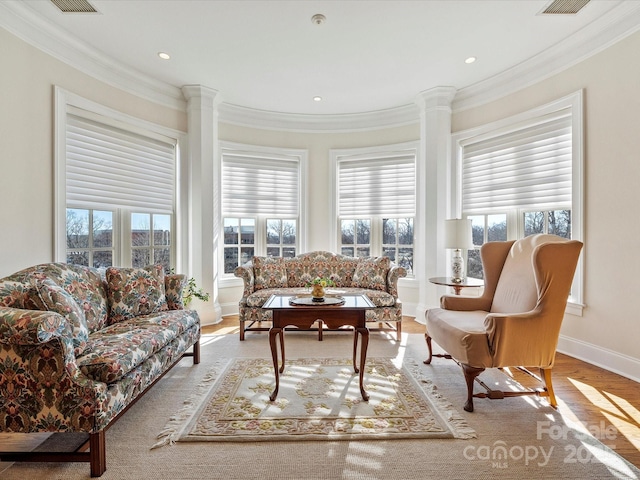 living room featuring wood-type flooring, ornamental molding, and ornate columns