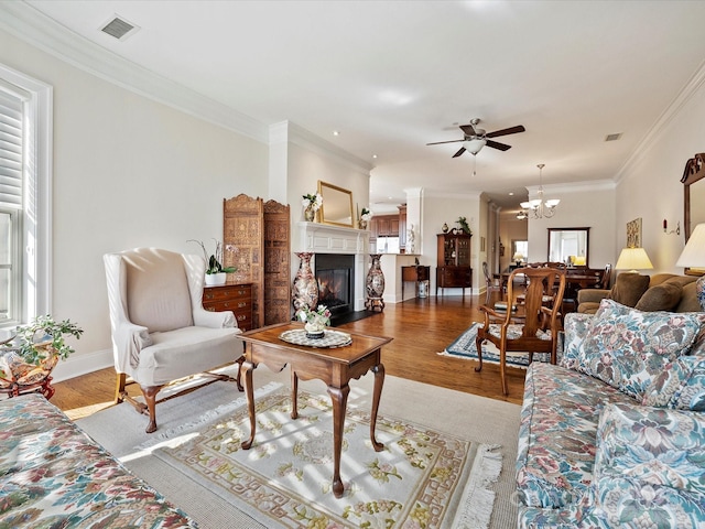 living room featuring hardwood / wood-style flooring, crown molding, and ceiling fan with notable chandelier