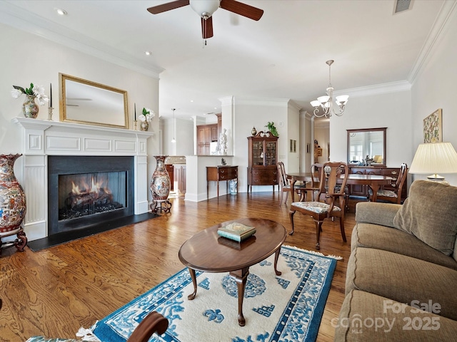 living room with ornamental molding, ceiling fan with notable chandelier, and wood-type flooring