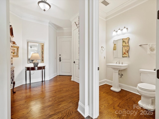 bathroom featuring hardwood / wood-style flooring, ornamental molding, and toilet