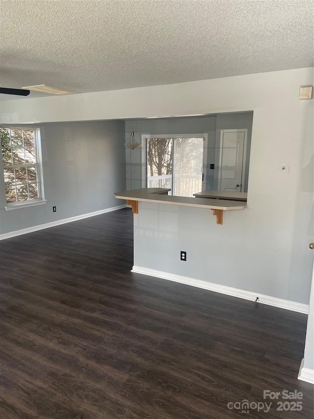 spare room featuring a healthy amount of sunlight, baseboards, and dark wood-style flooring