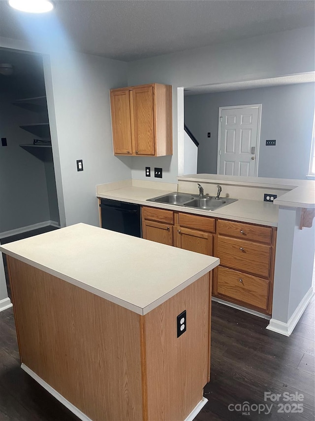 kitchen featuring black dishwasher, dark wood-style flooring, light countertops, and a sink