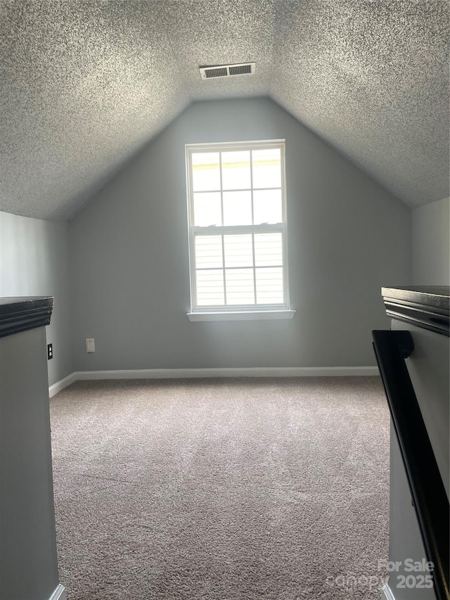 bonus room with vaulted ceiling, carpet flooring, visible vents, and baseboards