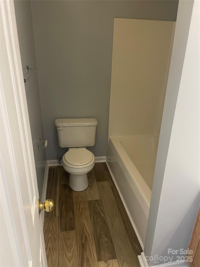 full bathroom featuring a bathtub, baseboards, toilet, and wood finished floors