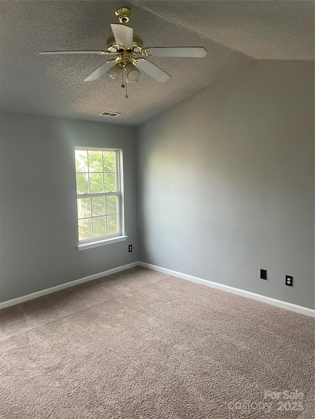 unfurnished room with baseboards, visible vents, lofted ceiling, a textured ceiling, and carpet flooring