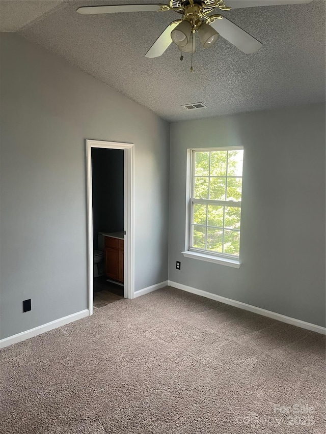 spare room featuring lofted ceiling, a textured ceiling, visible vents, baseboards, and carpet