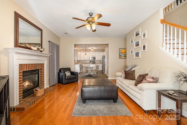 living room featuring hardwood / wood-style flooring, ceiling fan, and a fireplace