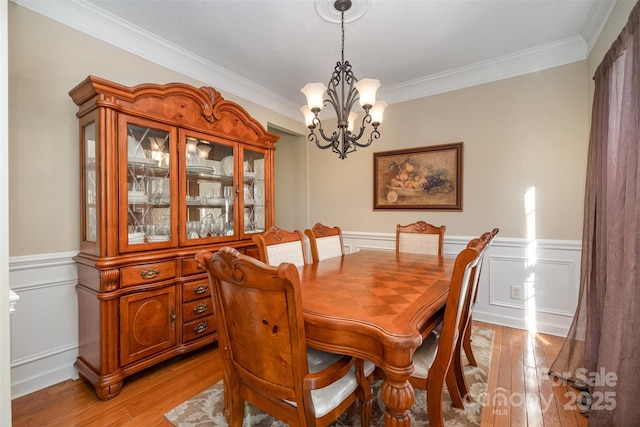 dining room featuring ornamental molding, light hardwood / wood-style flooring, and a notable chandelier