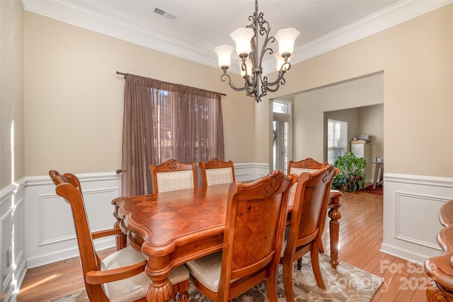 dining space featuring crown molding, light hardwood / wood-style floors, and a notable chandelier