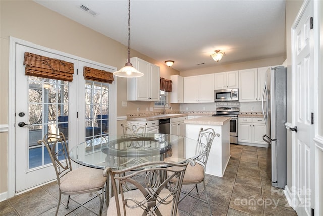 kitchen featuring stainless steel appliances, a center island, pendant lighting, and white cabinets