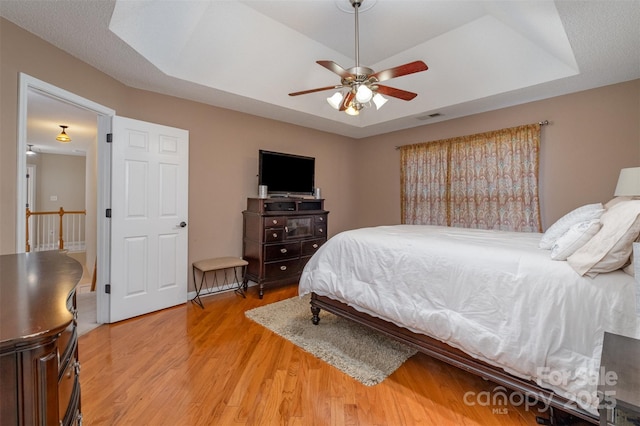 bedroom featuring hardwood / wood-style flooring, ceiling fan, and a tray ceiling