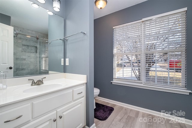 bathroom featuring tiled shower, vanity, toilet, and hardwood / wood-style floors