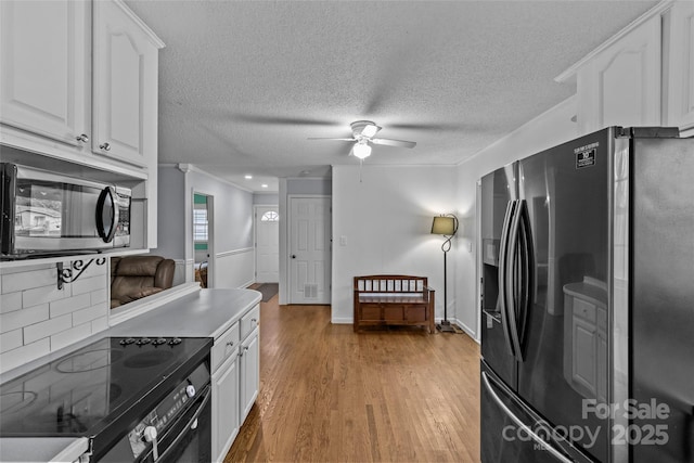 kitchen with crown molding, ceiling fan, white cabinetry, stainless steel appliances, and light wood-type flooring