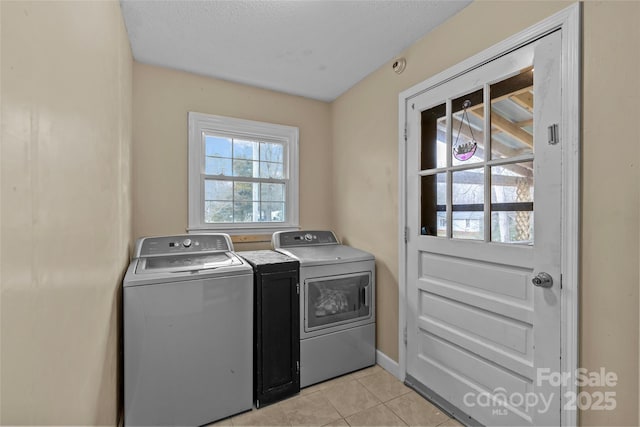 laundry room with washer and dryer, light tile patterned floors, and a textured ceiling