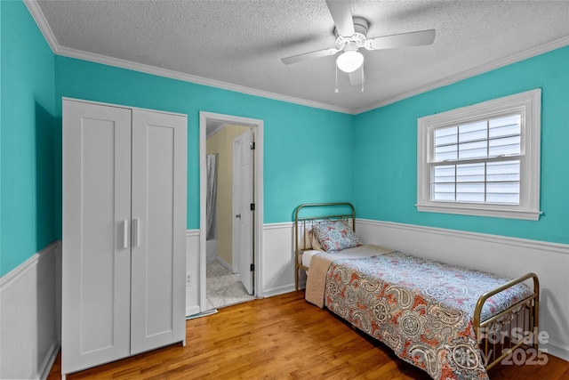 bedroom featuring light hardwood / wood-style flooring, ornamental molding, and a textured ceiling