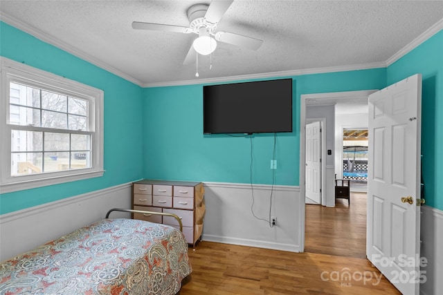 bedroom with wood-type flooring, ceiling fan, a textured ceiling, and crown molding