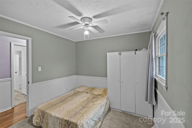 bedroom with ceiling fan, light hardwood / wood-style floors, crown molding, a textured ceiling, and a closet