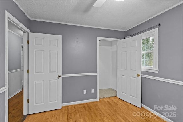 unfurnished bedroom with crown molding, ceiling fan, a textured ceiling, and light hardwood / wood-style flooring