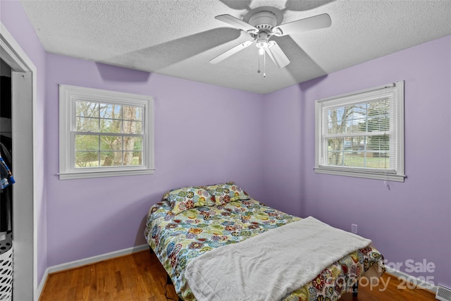 bedroom with multiple windows, hardwood / wood-style floors, and a textured ceiling