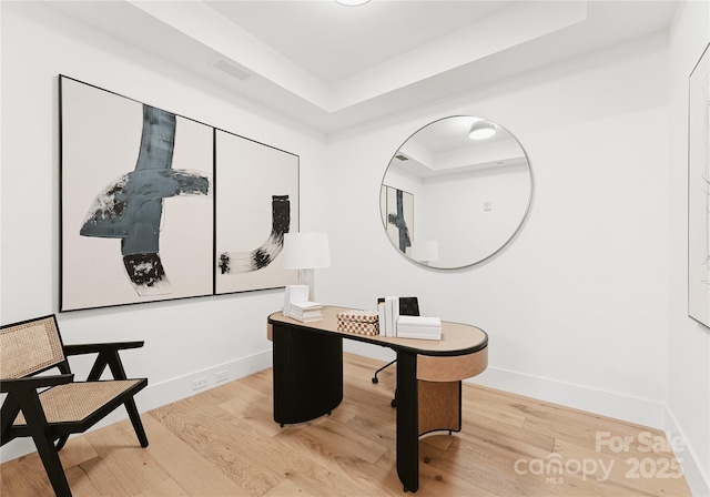 office space with a tray ceiling and hardwood / wood-style floors