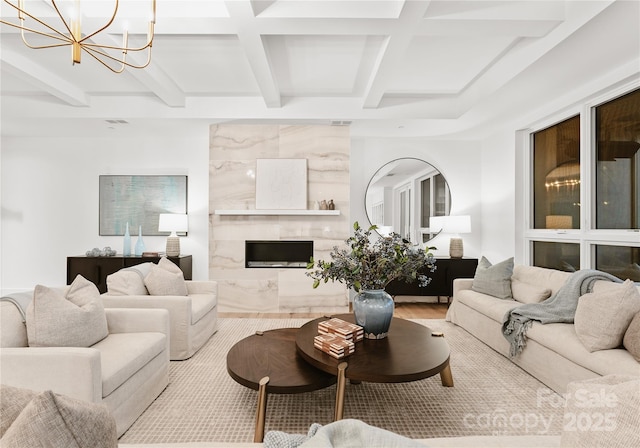 living room with coffered ceiling, beamed ceiling, a premium fireplace, and a chandelier