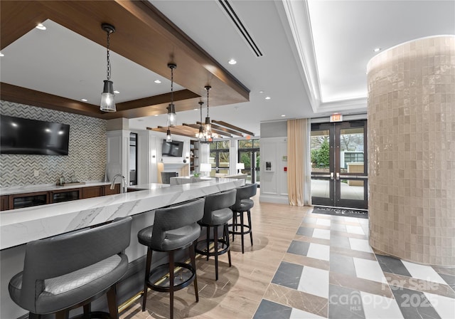 kitchen featuring decorative light fixtures, light stone countertops, a raised ceiling, and decorative backsplash