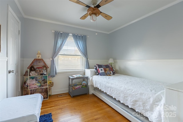 bedroom with crown molding, ceiling fan, and hardwood / wood-style floors