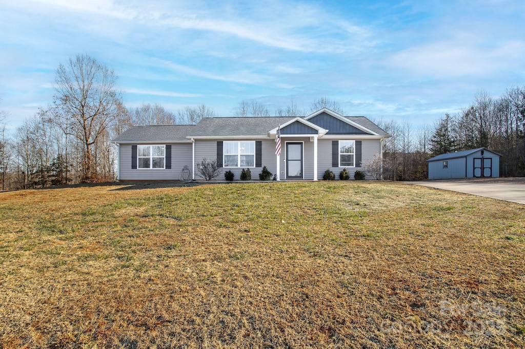 ranch-style home with an outdoor structure and a front lawn