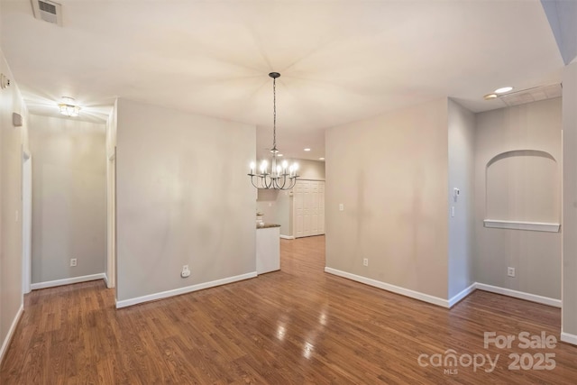 spare room featuring hardwood / wood-style flooring and a chandelier