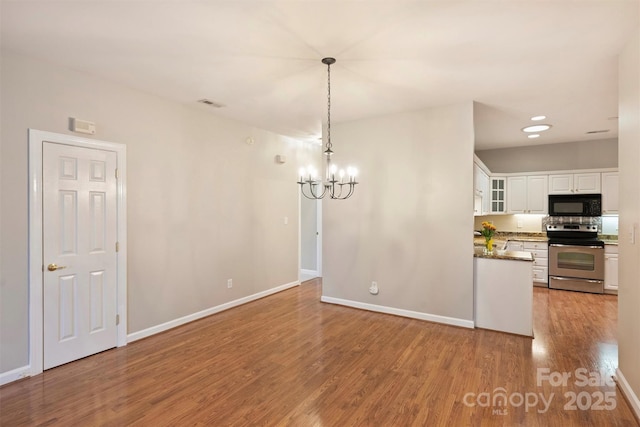 interior space featuring white cabinetry, a notable chandelier, light hardwood / wood-style floors, decorative light fixtures, and stainless steel electric stove