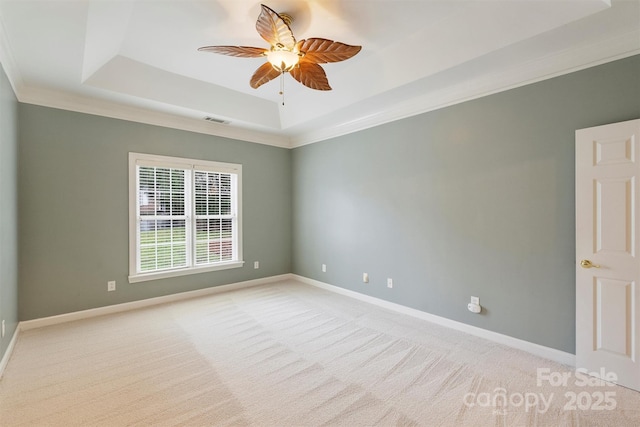 carpeted empty room featuring ornamental molding, ceiling fan, and a tray ceiling