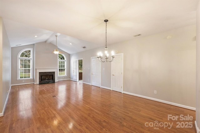 unfurnished living room with hardwood / wood-style floors, ceiling fan with notable chandelier, a fireplace, and vaulted ceiling with beams