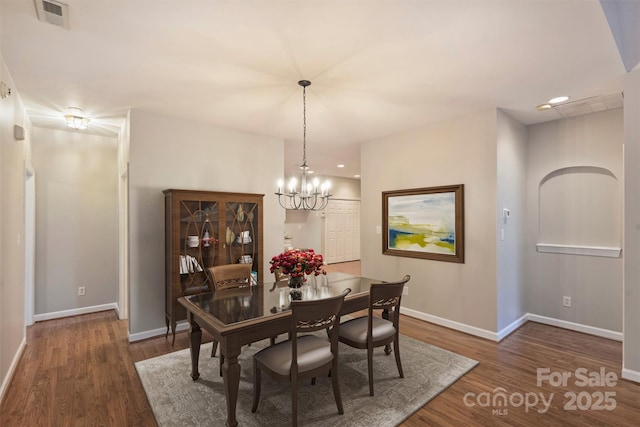 dining area with dark wood-type flooring and a chandelier