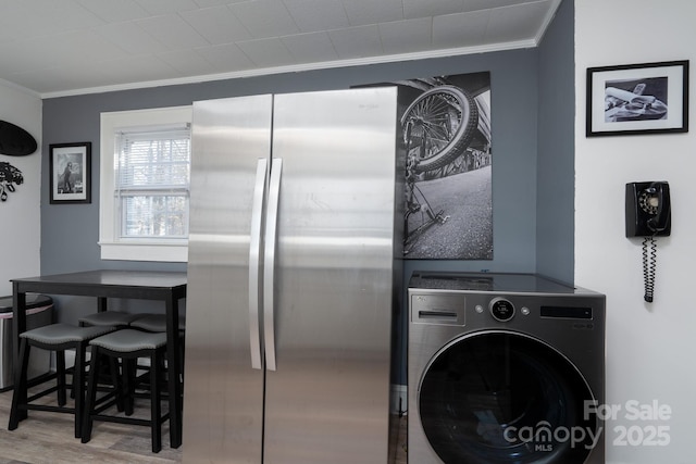 clothes washing area featuring washer / clothes dryer, ornamental molding, and hardwood / wood-style floors