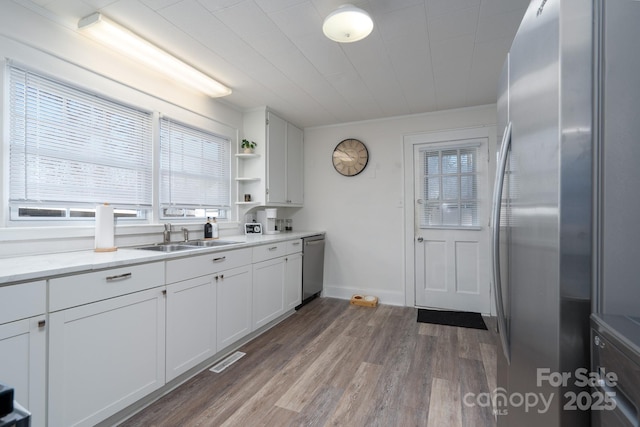 kitchen with white cabinetry, sink, wood-type flooring, and stainless steel appliances