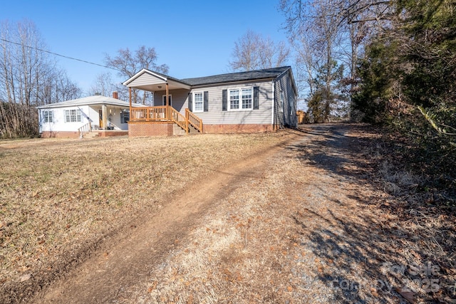 ranch-style home featuring covered porch and a front yard