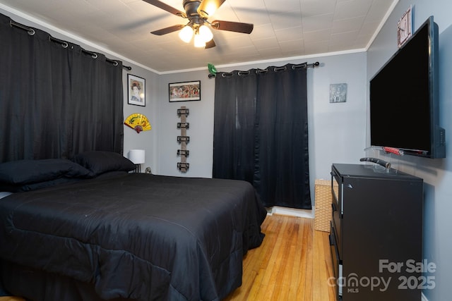 bedroom with ornamental molding, ceiling fan, and light hardwood / wood-style flooring