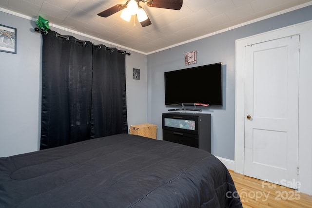 bedroom with ornamental molding, wood-type flooring, and ceiling fan