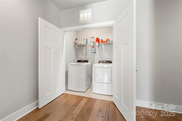 laundry room with separate washer and dryer and light hardwood / wood-style flooring