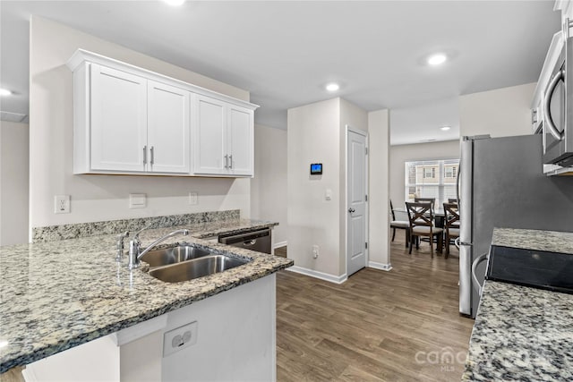 kitchen with sink, white cabinetry, light stone counters, dark hardwood / wood-style flooring, and stainless steel appliances